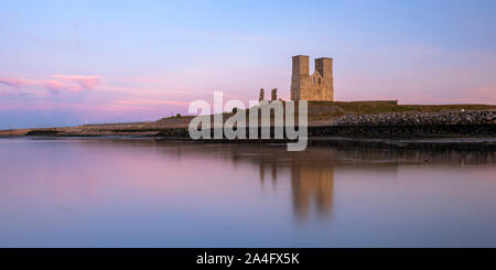 Reculver Tours ; une église médiévale et de l'emplacement d'un fort romain reflète dans la marée basse au coucher du soleil. Banque D'Images