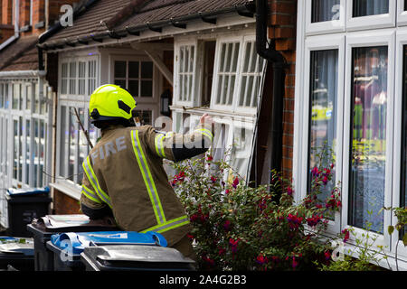 Un pompier regarde un ensemble de fenêtres avant endommagé après une grande explosion de gaz sur les jardins en terrasses, un Foxley street dans le sud de Londres. La chambre. Banque D'Images