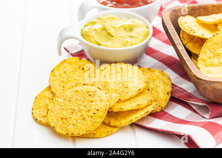 Croustilles de maïs ronde et avocat trempette. Croustilles de maïs jaune et de guacamole dans le bol sur le tableau blanc. Banque D'Images