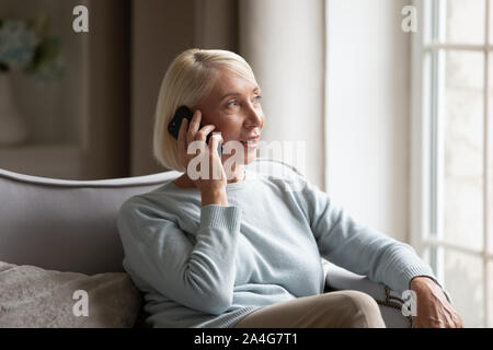 Heureux grand-mère parler avec petits-enfants via smartphone à la maison. Banque D'Images