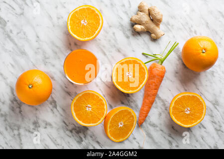 Orange en bonne santé, de carotte et de jus de gingembre. Composition sur fond de marbre blanc vu de dessus. Banque D'Images