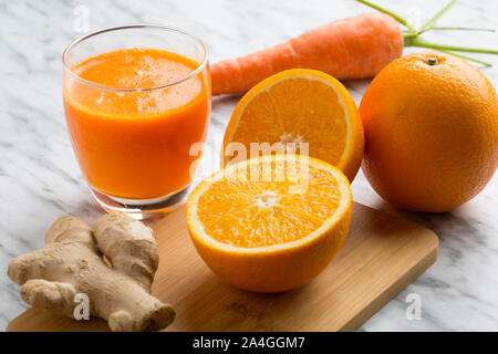 Orange en bonne santé, de carotte et de jus de gingembre. Composition sur fond de marbre blanc vu de dessus. Banque D'Images