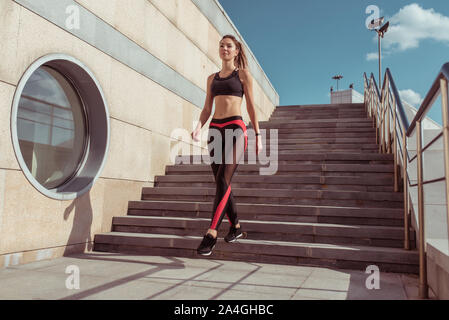 Fille de sports va dans summer city. Leggings vêtements de dessus. L'étape historique. La motivation à l'entraînement de forme physique de vie. L'espace libre du texte. Tannés et slim Banque D'Images