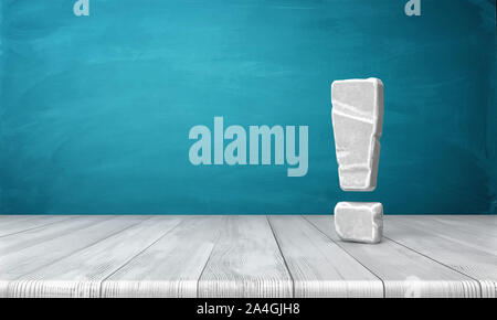 Le rendu 3D d'un point d'exclamation blanc-gris en pierre debout sur une surface en bois en face de fond bleu. Banque D'Images