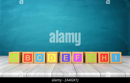 Le rendu 3D d'un grand nombre de blocs de jouets colorés avec des lettres de l'alphabet anglais sur une longue ligne sur un bureau en bois. Banque D'Images