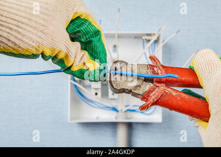 Le câblage domestique service. L'utilisation de pinces fin aux travaux électriques dans la chambre. L'arrêt de la partie de l'électricien le câble d'alimentation lors de l'installation d'un swit Banque D'Images