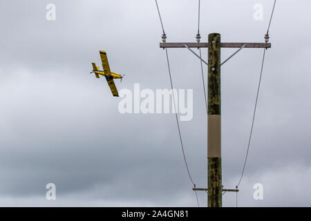 Sheffield, Canterbury, Nouvelle-Zélande, le 14 octobre 2019 : Une récolte jaune duster, ou terreautage avion, passe sur les lignes électriques basse comme il se propage l'engrais Banque D'Images