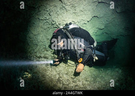 Un plongeur sort d'une petite grotte passage dans Angelita cenote au Mexique. Banque D'Images