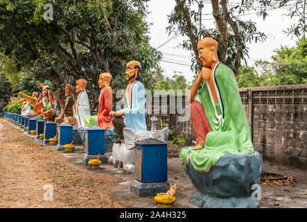 Bang Saen, Thaïlande - Mars 16, 2019 : Wang Saensuk monastère Bouddhiste. Rangée de statues colorées de dix-huit saints chinois sous le feuillage vert. Banque D'Images