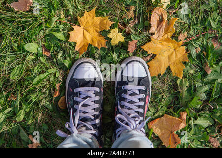 Pieds de vieilles chaussures sur le passé l'automne feuilles d'érable. Vue d'en haut Banque D'Images