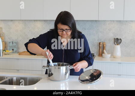 Maman cuisiniers soigneusement pour sa famille dans la cuisine Banque D'Images