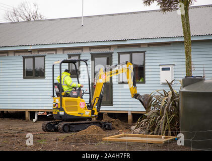 Un constructeur creuse une tranchée sur un chantier pour poser des câbles d'alimentation et de l'eau dans la région de Canterbury, Nouvelle-Zélande Banque D'Images