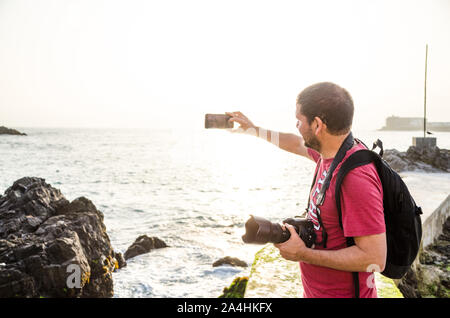 Un homme prenant un photographe sur selfies une journée ensoleillée à la plage Banque D'Images