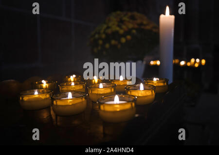 Petite prière ou votive candles burning en ex-voto dans un acte de la prière chrétienne à l'intérieur de l'église Banque D'Images