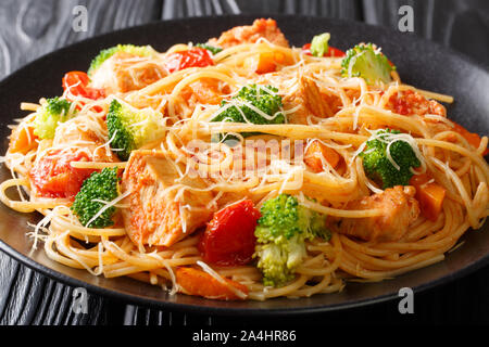 Les pâtes spaghetti avec brocoli, poulet et potiron à la sauce tomate sur une plaque horizontale sur la table. Banque D'Images