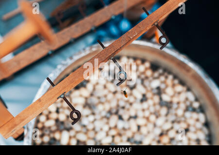 Les cocons de vers à soie dans l'eau chaude dans un chaudron. Rouet traditionnel machine permettant de fabriquer de la soie naturelle ver à soie. Processus de dévidage de la soie. Banque D'Images