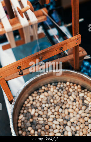 Les cocons de vers à soie dans l'eau chaude dans un chaudron. Rouet traditionnel machine permettant de fabriquer de la soie naturelle ver à soie. Processus de dévidage de la soie. Banque D'Images