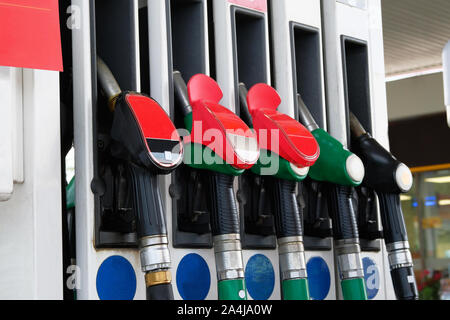 L'essence et des produits pétroliers concept. Pistolets de carburant rouge et noir sur station de carburant. L'essence à la pompe à essence de pompage. Close up. Banque D'Images