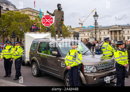 L'Extinction d'un manifestant de la rébellion se dresse au sommet d'une voiture tenant un panneau d'arrêt rouge tout en étant entouré par la police en fluorescent yellow jackets,Londres, 7 octobre 2019 Banque D'Images