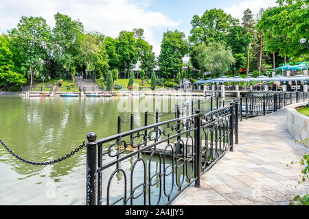 Almaty Central Park Village pittoresque vue imprenable sur un lac avec bateaux ancrés et une promenade clôturé sur un ciel bleu ensoleillé Jour Banque D'Images