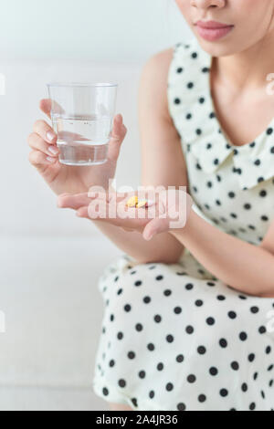 Femme avec des pilules et verre d'eau à l'intérieur Banque D'Images