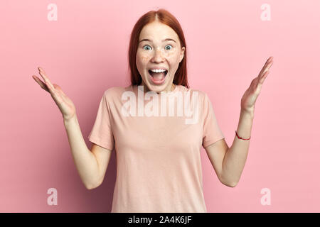 Red-haired heureux heureux cheerful young woman laughing, cris, élever les mains, , sur fond rose, isolé. portrait, réaction, position Banque D'Images