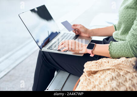 Les jeunes filles asiatiques holding credit card and using laptop computer shopping online lors de la vérification de vol ou l'enregistrement en ligne à l'aéroport Banque D'Images