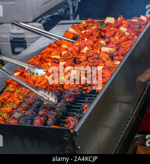 Griller les brochettes de poulet à un stand de nourriture jamaïcaine dans un marché de nuit Banque D'Images