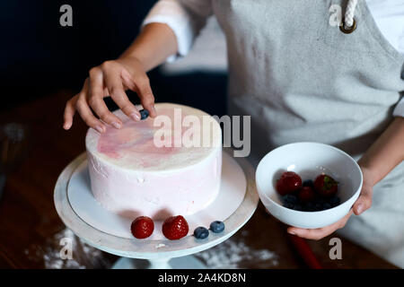 Woman putting berries sur dessert, de l'art , la créativité, Close up photo recadrée Banque D'Images