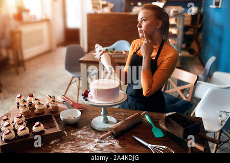 Sérieux attentionné cook avec un doigt sur son menton penser comment décorer un dessert, d'une décoration, Close up side view photo Banque D'Images