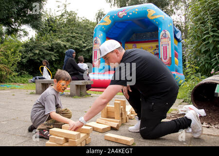 Sheffield, UK : 1 août 2016:Un jeune garçon jouer Jenga géant avec un The Timebuilders bénévole à l'église St Mary Family Fun Day Banque D'Images