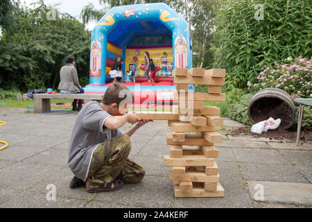 Sheffield, UK : 1 août 2016:Un jeune garçon jouer Jenga géant avec un The Timebuilders bénévole à l'église St Mary Family Fun Day Banque D'Images