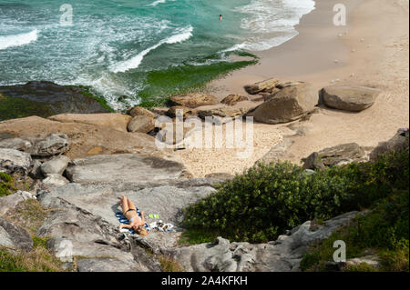 27.09.2019, Sydney, Nouvelle-Galles du Sud, Australie - une femme de soleil sur les rochers à la plage de Tamarama. Banque D'Images