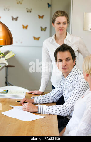 Jeune couple de signer les documents de vente. L'achat première maison. L'achat d'une télévision. Contrat. Accord. L'investissement. Banque D'Images