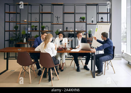 Les jeunes gens assis au bureau, la création de nouveaux produits à la mode, photo pleine longueur. Intérieur moderne Banque D'Images