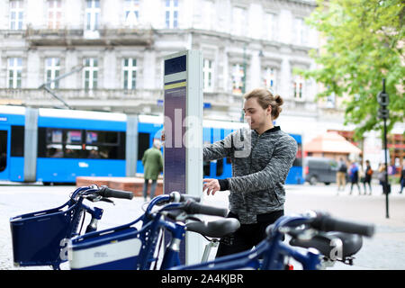 Jeune garçon en vélo, avec l'embauche de la machine en ville, route et trafic piétons en arrière-plan. Banque D'Images