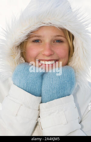Girl wearing white manteau avec capuche et moufles bleu Banque D'Images