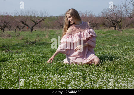 Femme blonde recueille des fleurs dans le jardin en fleurs Banque D'Images