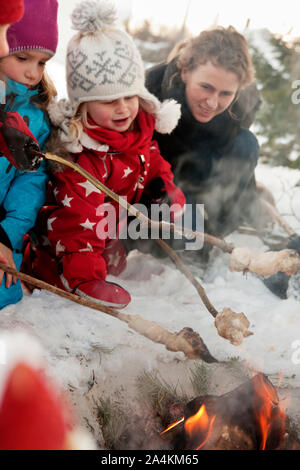 Griller le pain des enfants sur un feu de camp Banque D'Images