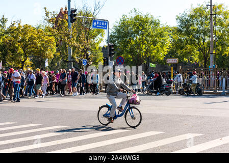 Un homme monté sur un vélo acrossing la rue avec beaucoup de gens à pied, dans la vieille ville de Pékin, Chine Banque D'Images
