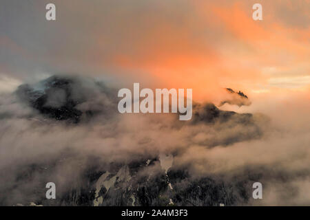 Vue aérienne de la montagne mur Troll dans une mer de nuages au coucher du soleil, la vallée de Romsdalen, Andalsnes, More og Romsdal County, Norvège Banque D'Images