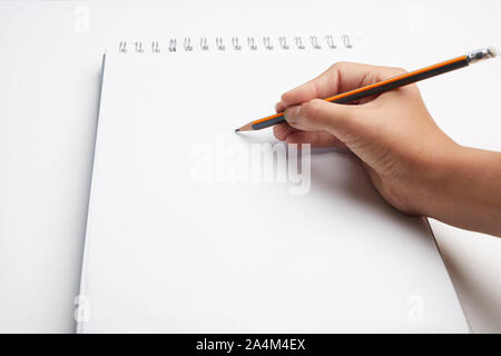 Hand holding pen écrit en blanc sur fond blanc. Écrire à la main dans le livre blanc feuille vierge. Banque D'Images