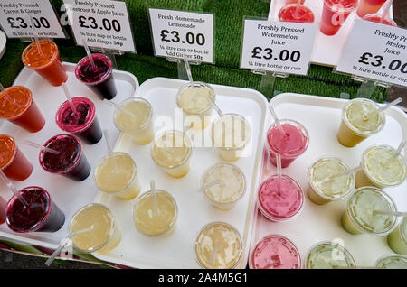 Échoppe de marché avec divers jus de fruits frais dans des gobelets en plastique. Avec des prix. Vue d'en haut. Banque D'Images