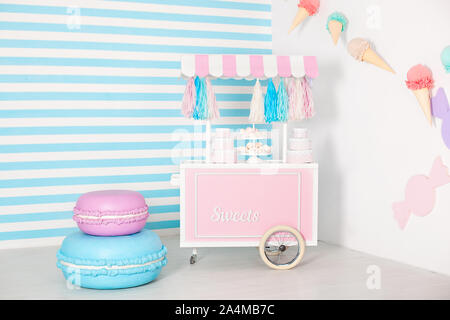 Chambre d'enfant avec une bande bleue fond. candy photo blocage zone avec gros macarons, bonbons et guimauves. Panier avec Candy Bar. Décorée Banque D'Images