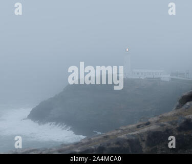 Pile du Sud, l'Île Sainte / Pays de Galles - 14 février 2018 - La pluie et le brouillard cache phare de South Stack en tempête avec des vagues qui Banque D'Images