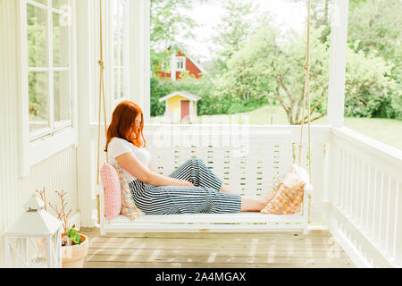 Femme assise sur swing en terrasse Banque D'Images