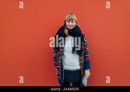 Young woman wearing scarf sur fond rouge Banque D'Images