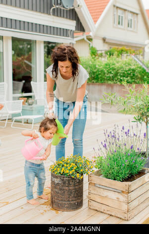 Mère fille avec l'arrosage des plantes on patio Banque D'Images