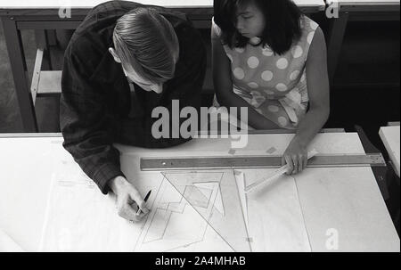 Années 1960, histoire, deux nouveaux étudiants, un homme et une femme assis ensemble au bureau dans un cours de conception et de construction à l'Université de Californie du Sud, États-Unis. Un triangle et une règle sont sur le bureau, car la géométrie fait partie du cours. Banque D'Images