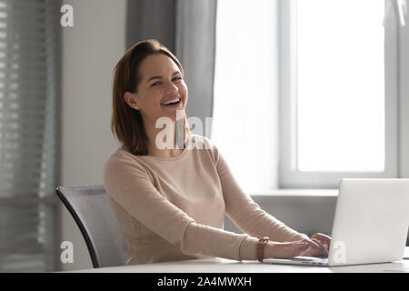 Portrait of happy laughing businesswoman working on laptop in office Banque D'Images